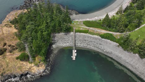 High-up-aerial-shot-of-a-lone-dock-extending-out-onto-a-shallow-cove-of-water-on-Whidbey-Island