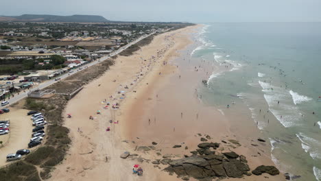 Flying-over-beautiful-beach-with-many-people-enjoying-their-vacations-in-rural-Spain