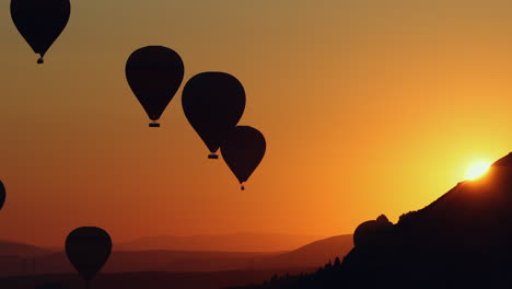 Early-morning-sunrise-hot-air-balloon-rides-over-the-mountains-in-Love-Valley-in-Cappadocia,-Turkey
