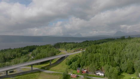 Carretera-Que-Entra-En-El-Bosque-Drone-Aéreo-Narvik-Noruega-Paisaje-Del-Norte-Luz-Del-Sol-En-Los-árboles-Y-Montañas