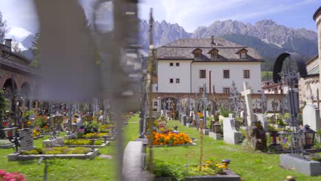 Tracking-shot-of-rows-of-graves-with-iron-crosses-in-the-cemetery-of-the-Collegiate-church-in-San-Candido,-Italy