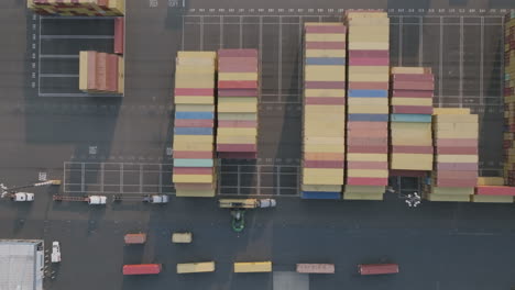 Top-down-sped-up-aerial-footage-of-a-loader-loading-up-semi-trucks-with-shipping-containers