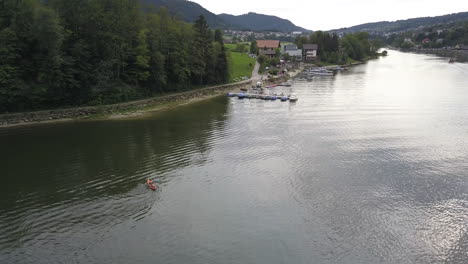 Ein-Kleines-Boot-Fährt-Auf-Einem-Flachen-Bach-In-Ufernähe-Mit-Tannenwald,-Fluss-In-Der-Schweiz:-Doubs