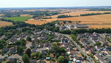 Luftaufnahmen-Des-Kleinen-Dorfes-Acton-In-Suffolk,-Umgeben-Von-Ackerland-Und-Goldenen-Feldern