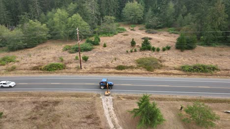 Wide-aerial-shot-of-a-tractor-with-a-slope-and-ditch-mower-attachment-cutting-the-weeds