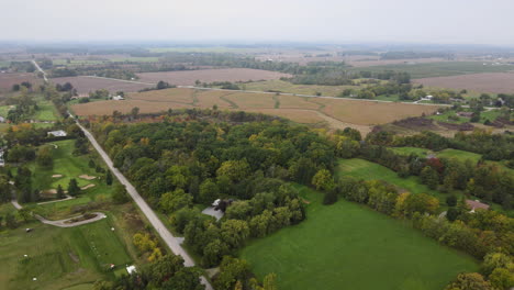 Aerial-High-Altitude-View-of-Countryside-Nature-Landscape-in-Autumn-Season,-Rural-Roads-next-to-Green-Park-Golf-Course-Field-and-Vast-Agricultural-Lands-Around,-Skyline-in-Horizon