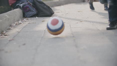 Slow-motion-footage-of-a-kid-chasing-a-striped-ball-in-a-square-in-Antigua,-Guatemala