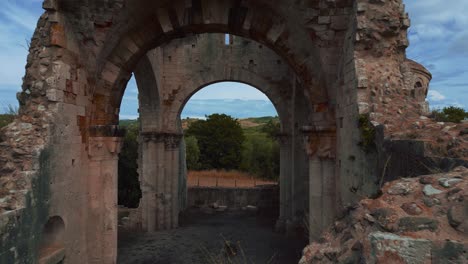 Flying-through-old-Abbazia-di-San-Bruzio,-a-damaged-ruin-of-an-abandoned-medieval-monastery-abbey-church-in-Tuscany-of-the-11th-century-surrounded-by-olive-trees-in-Italy