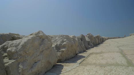 Camera-shot-to-the-back-of-a-beach-promenade-with-stones-in-Caorle-in-Italy-during-a-sunny-day-on-vacation