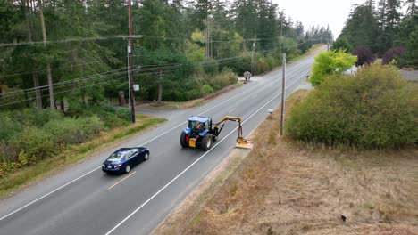 Drone-shot-following-a-tractor-with-a-mowing-attachment-as-it-helps-clean-the-local-roadside-on-Whidbey-Island