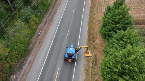 Overhead-aerial-shot-of-a-tractor-with-a-slope-and-ditch-mower-attachment-as-it-cleans-up-the-local-ditches