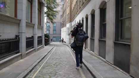 Videographer-walking-down-city-street-on-his-way-to-film-shoot