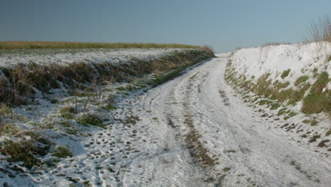 Melting-snow-on-a-path-in-the-belgian-countryside-in-winter-and-blue-sky