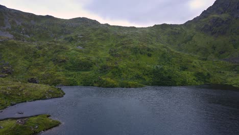 Agua-Desbordante-Que-Se-Libera-De-Un-Depósito-Construido-En-Una-Montaña-Rocosa-Verde-En-Escandinavia