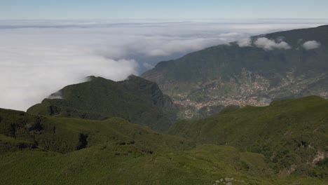Fliegen-über-Den-Wolken-Und-Den-Grünen-Bergen-Der-Insel-Madeira,-Drohne-Fliegt-Vorwärts-Und-Enthüllt-Die-Gemeinde-Sao-Vicente-Auf-Der-Insel-Madeira,-Blick-Von-Paul-Da-Serra
