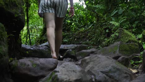 A-lady-walking-on-a-damp-rocky-trail-through-the-lush-rainforest