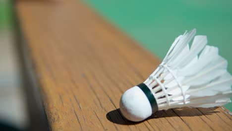 Badminton-shuttlecock-on-a-wooden-fence-near-an-outdoor-green-court---close-up