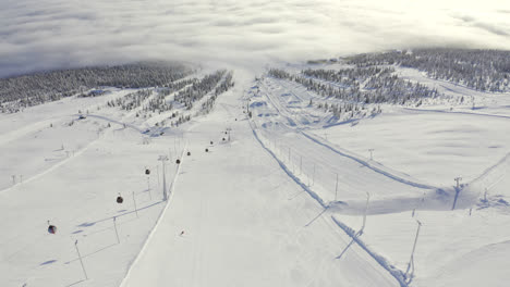 Aerial-view-flying-above-a-ski-resort-slope-with-a-person-curving-on-the-slope-with-skis