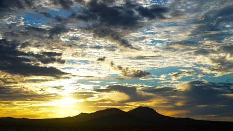 A-brilliant-golden-sunset-above-the-rugged-mountainous-terrain-of-the-Mojave-Desert---time-lapse
