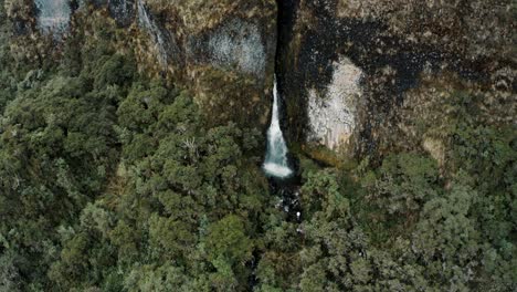 Vista-Aérea-De-La-Cascada-Que-Fluye-Hacia-El-Exuberante-Bosque-Verde-En-La-Reserva-Ecológica-De-Cayambe-Coca-En-Napo,-Ecuador