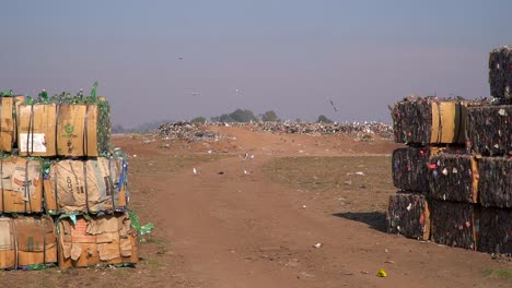 Vögel-überfliegen-Eine-Müllhalde-Zwischen-Verdichteten-Abfallwürfeln,-Die-Zum-Recycling-Bereit-Sind