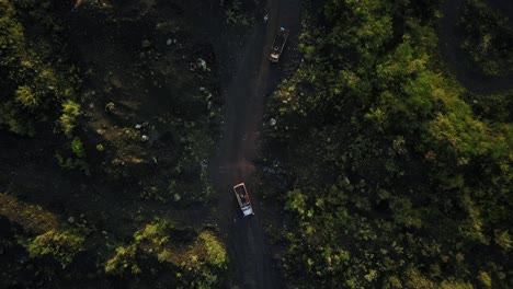 Aerial-top-down-shot-of-trucks-transporting-sand-of-sand-mine-between-destroyed-rainforest