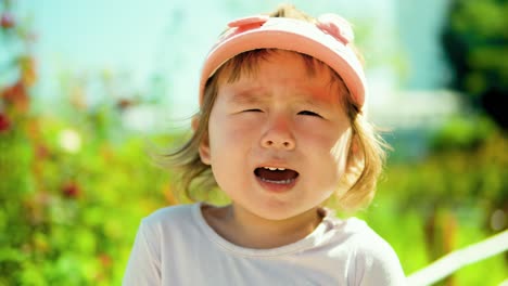 Pretty-blonde-toddler-girl-crying-while-looking-at-camera-at-the-park---face-close-up-on-sunny-summer-day