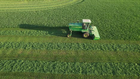 In-Door-County,-WI,-a-farmer-on-a-John-Deere-tractor,-cuts-his-alfalfa-field-in-late-August-16