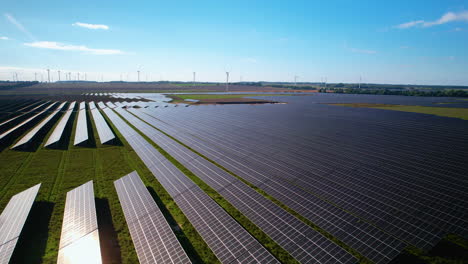 Large-Blue-Solar-Panels-In-A-Farmland-And-Wind-Turbines-At-The-Background