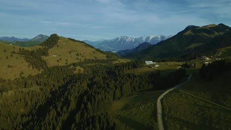 Green-grass-meadows-in-the-romantic-and-idyllic-Bavarian-Austrian-Sudelfeld-Wendelstein-alps-mountain-peaks-with-panorama-view-road
