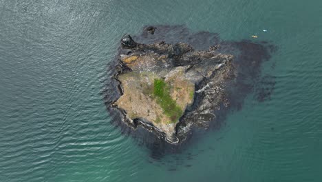 A-top-down-drone-shot-of-a-small-island-with-kayakers-surrounding-it