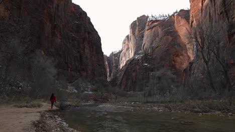 Woman-walking-next-to-a-flowing-river-in-the-Zion-National-Park