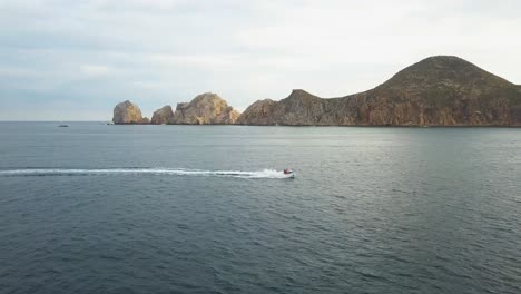 Panning-view-of-beautiful-rocky-hills-of-the-famous-Arch-landmark-in-the-background-and-a-fast-jet-ski-crossing-it