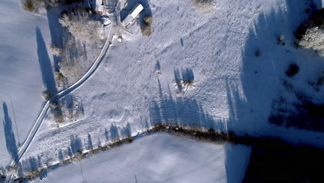 Flying-over-snow-covered-farmland-fields---straight-down-bird's-eye-view-of-a-winter-landscape