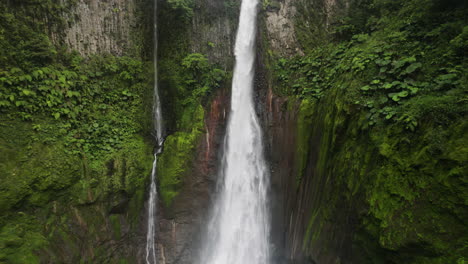 Die-Neigung-Aus-Der-Luft-Nach-Oben-Zeigt-Zwei-Wasserfälle-Im-Dschungel,-Die-über-Die-Klippenkante-Stürzen