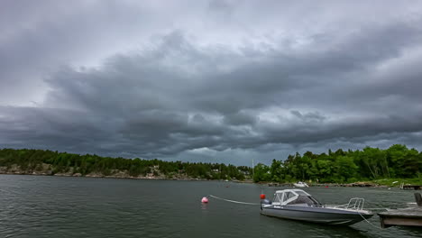 A-boat-docked-at-a-lake-in-Sweden-with-a-dark-ominous-cloudscape-overhead---time-lapse
