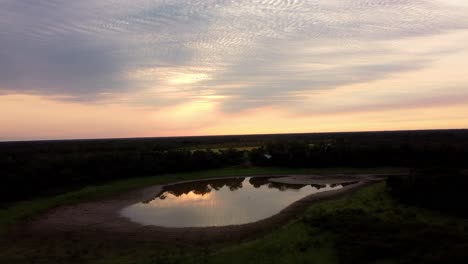 Friedlicher-Natürlicher-Teich-Auf-Grünen-Feldern-Mit-Wasserreflexion-Bei-Sonnenaufgang,-Paraguay