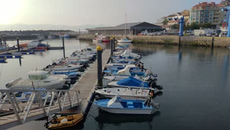 Un-Pescador-Prepara-Herramientas-Entre-Los-Barcos-De-Pesca-Amarrados-En-El-Muelle-Del-Puerto-Con-Acceso-Por-La-Rampa-A-La-Plataforma-En-Una-Tranquila-Y-Soleada-Mañana-De-Verano,-Tiro-Bloqueado