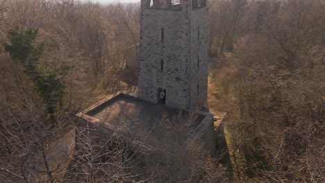Static-Aerial-Shot-Through-A-Bare-Tree-Of-A-Young-Man-Exploring-The-First-Level-Of-The-Wetzlar-Tower