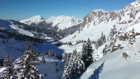 Low-flyover-through-back-country-of-Avoriaz-Ski-Resort,-French-Alps-towards-groomed-ski-run