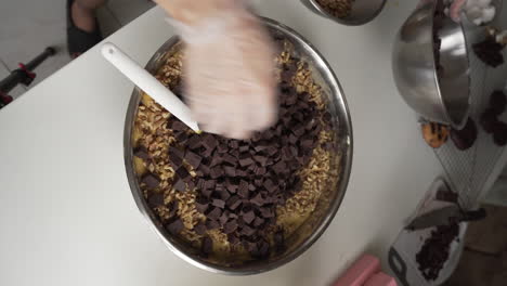 Bäcker-Gießt-Gehackte-Dunkle-Schokolade-In-Die-Keksteigmischung