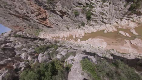 FPV-flight-dives-fast-from-rugged-canyon-rim-to-narrow-river-below