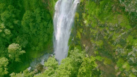Roaring-waterfall-plunges-into-a-ravine-surrounded-by-a-verdant-rainforest
