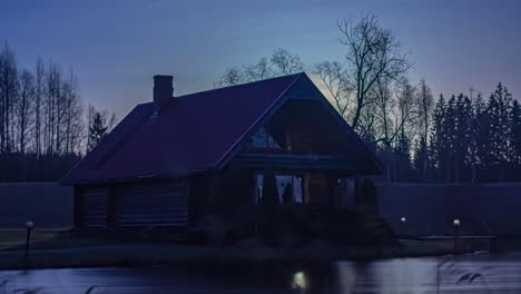 Static-view-of-sun-rising-in-timelapse-over-a-lake-in-front-of-a-wooden-cottage-during-early-morning