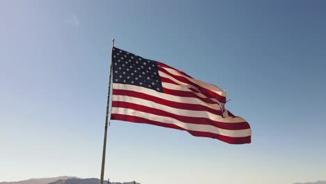 Bandera-Americana-Que-Sopla-En-El-Viento,-Fondo-De-Cielo-Azul