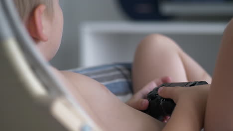 Rear-closeup-of-shirtless-young-boy-child-play-games-holding-controller,-indoor