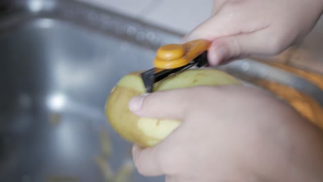 Hand-using-peeler-to-peel-potato-skin-preparing-for-cooking