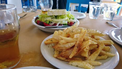 Hand-held-Footage-Of-A-Freshly-Prepared-Greek-Salad-And-A-Plate-Of-Chips,-Served-Within-A-Outside-Restaurant
