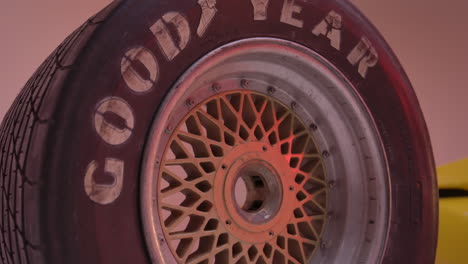 4k-huge-truck-tire-standing-on-top-of-another-tire-with-golden-rims-in-a-red-lit-studio