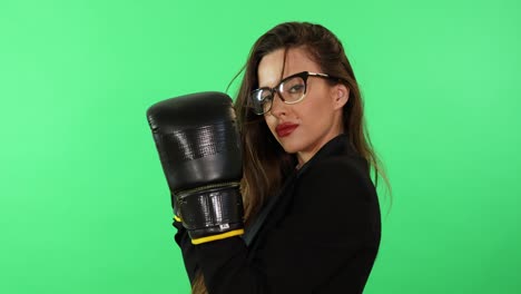 Sexy-and-seductive-brunette-young-woman-with-glasses-and-business-dress-wear-boxing-gloves-ready-to-fight-daily-life-stress